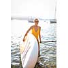 SUP Stand up paddle board concept - Pretty, young woman paddle boarding on a lovely lake in warm late afternoon light