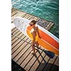 SUP Stand up paddle board concept - Pretty, young woman paddle boarding on a lovely lake in warm late afternoon light