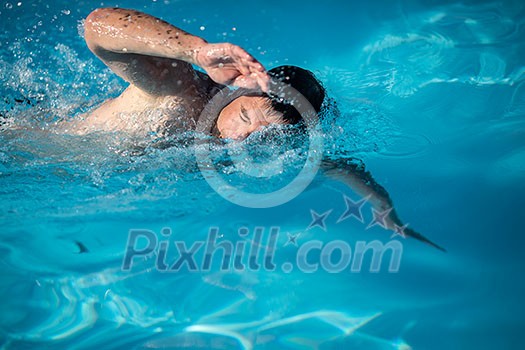 Male swimmer swimming crawl in an outdoor pool - keeping fit Male swimmer swimming crawl in an outdoor pool - keeping fit