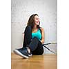 Cute young woman with a racket leaning against a wall in a squash court, ready for the game