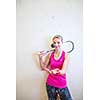 Cute young woman with a racket leaning against a wall in a squash court, ready for the game