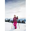 Pretty, young woman snowshoeing in high mountains, enjoying splendid winter weather with abundance of snow