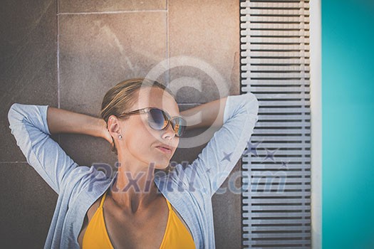 Young Beautiful Suntanned Woman wearing sunglasses relaxing next to a Swimming Pool on a lovely Summer Day Young Beautiful Suntanned Woman wearing sunglasses relaxing next to a Swimming Pool on a lovely Summer Day