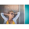 Young Beautiful Suntanned Woman wearing sunglasses relaxing next to a Swimming Pool  on a lovely Summer Day