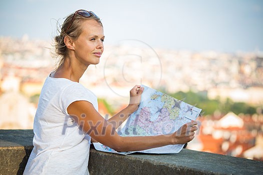 Pretty young female tourist studying a map at the Trajan's forum in Rome, Italy (dome of the Santissimo Nome di Maria church in the background)