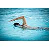 Man swimmer swimming crawl in a blue water  pool. Portrait of an athletic young male triathlete swimming crawl wearing swimming goggles. Triathlete training for triathlon.