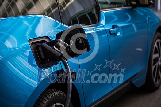 Power supply for electric car charging. Electric car charging station. Close up of the power supply plugged into an electric car being charged.