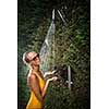 Beautiful young woman taking a shower outdoors. Attractive young woman in yellow one-piece enjoys shower on hot sunny day after a swim. Heat and refreshment concept.