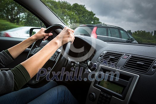 Female driver's hands driving a car on a highway (color toned image; shallow DOF)
