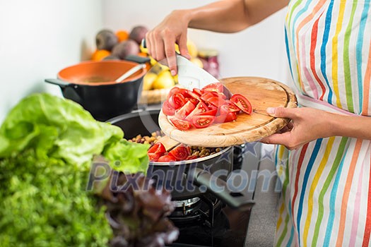 Young woman cutting vegetables in her modern kitchen - fixing a salad