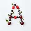 Letter A english alphabet in the form of a pattern of natural organic berries - ripe fresh raspberry, black currant, cherry, green mint leaf isolated on a white background. Flat lay
