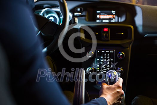 Driving a car at night - pretty, young woman driving her modern car at night, in a city (shallow DOF; color toned image)