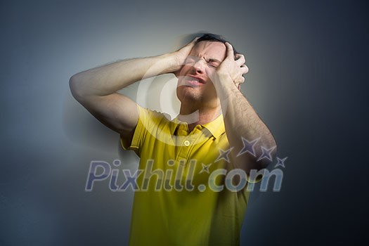 Young man suffering from an intense headache/migraine/anxiety attack - color toned image