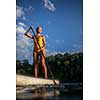 SUP Stand up paddle board concept - Pretty, young woman paddle boarding on a lovely lake in warm late afternoon light