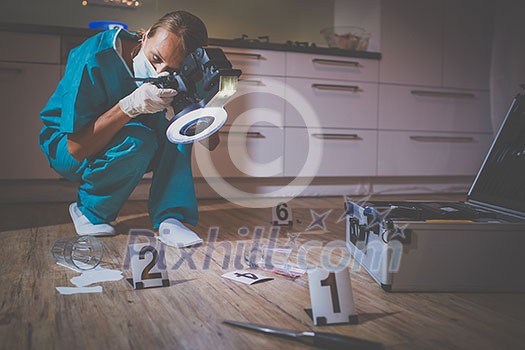Forensic specialist in protective suit taking photos on a crime scene Forensic specialist in protective suit taking photos on a crime scene