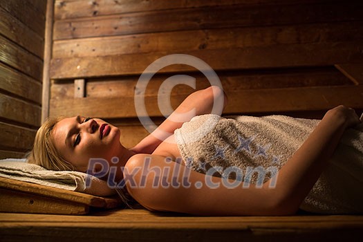 Young woman relaxing in a sauna, taking a break from her busy schedule, taking care of herself, enjoying the wellness benefits her job provides Young woman relaxing in a sauna, taking a break from her busy schedule, taking care of herself, enjoying the wellness benefits her job provides