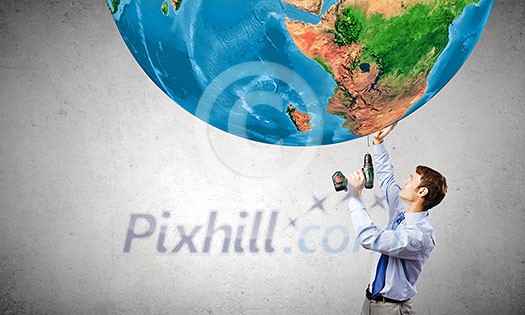 Young businessman drilling Earth planet. Elements of this image are furnished by NASA Young businessman drilling Earth planet. Elements of this image are furnished by NASA