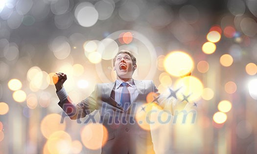 Young handsome businessman with hands up celebrating success