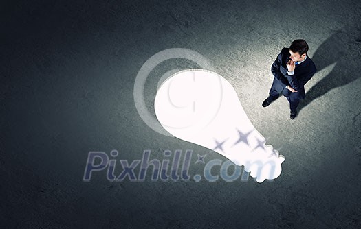 Top view of businessman looking at bulb on floor