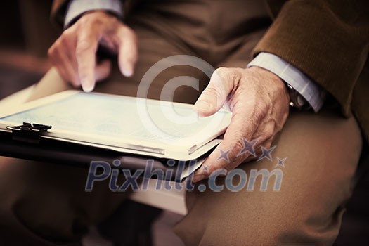 Closeup of mature hands holding tablet. Teacher with students in classroom