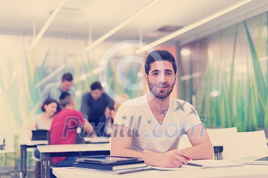 male student in classroom working homework and learning with laptop computer, students group in background male student in classroom working homework and learning with laptop computer, students group in background