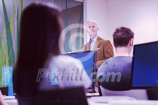 handsome mature teacher and students in computer lab classroom handsome mature teacher and students in computer lab classroom
