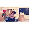 Relaxing in new house. Cheerful young couple sitting on the floor while cardboard boxes laying all around them