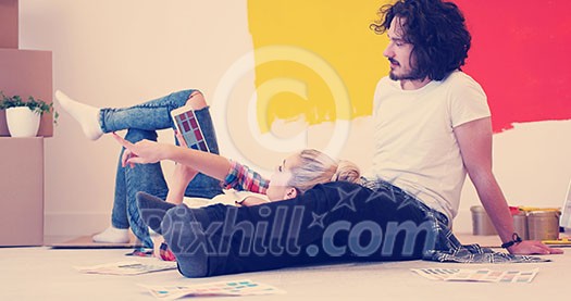 Happy young couple relaxing after painting a room in their new house on the floor Happy young couple relaxing after painting a room in their new house on the floor