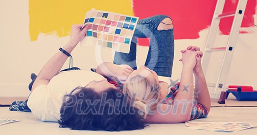 Happy young couple relaxing after painting a room in their new house on the floor Happy young couple relaxing after painting a room in their new house on the floor
