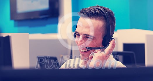 young smiling male call centre operator doing his job with a headset young smiling male call centre operator doing his job with a headset