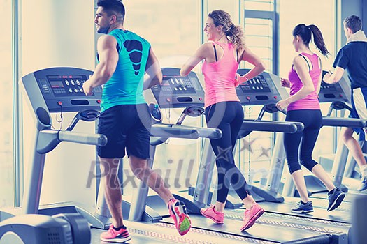 group of young people running on treadmills in modern sport gym group of young people running on treadmills in modern sport gym