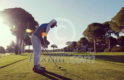 golf player hitting shot with club on course at beautiful morning with sun flare in background golf player hitting shot with club on course at beautiful morning with sun flare in background