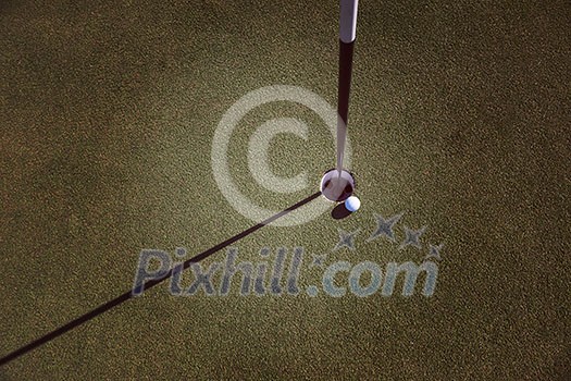 top view of golf ball on edge of course hole representing achivement and success business concept top view of golf ball on edge of course hole representing achivement and success business concept