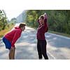 young couple enjoying in a healthy lifestyle while warming up and stretching before running on a country road, exercise and fitness concept