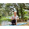 healthy woman relaxing while meditating and doing yoga exercise in the beautiful nature on the bank of the river