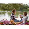 Couple in love enjoying picnic time drink and food in beautiful nature on the river bank