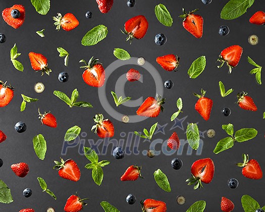 Top view of colorful composition of strawberry red ripe, blueberry and green sprig of mint isolated on black background