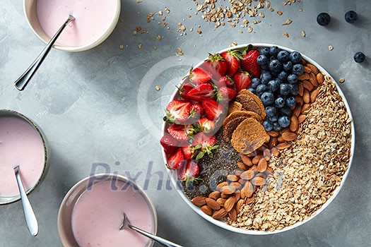 Useful ingredients for making breakfast from yoghurt in bowl, chia, berries and oatmeal on a plate on stone light background. Antioxidant, superfood, ideal for breakfast top view