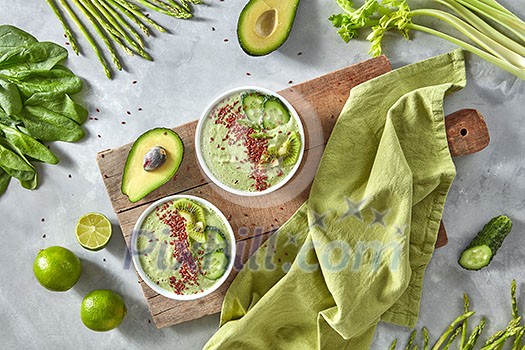 Vegetable green smoothies with flax and kiwi in a plate on an old wooden board with a kitchen towel around a set of vegetables, avocado, cucumber, spinach, asparagus, lime, celery. Healthy Vegetarian Food. Flat lay