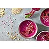 Red smoothies with strawberries and bluevberries, oatmeal flakes and candies hearts on a concrete background with halves of a young beetroot, flat lay
