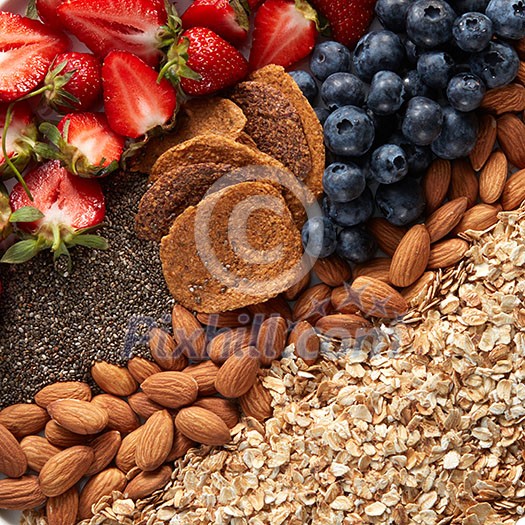 Close-up of a set of ingredients, oatmeal, granola, almonds, snacks, blueberries and strawberries halves top view. Healthy vitamin breakfast