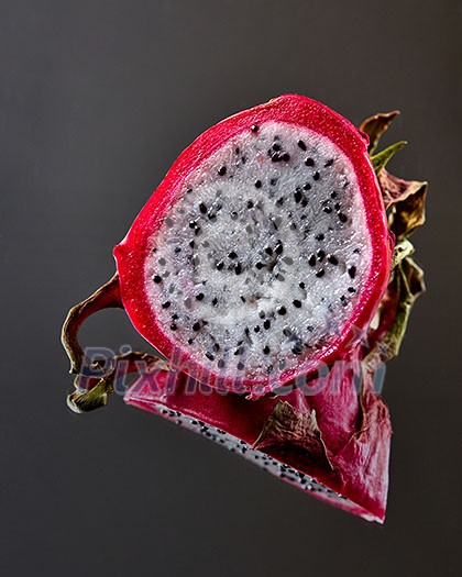 Ripe halves of tropical fruit pitahaya or Dragon fruit isolated on a black glossy background with reflection