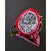 Ripe halves of tropical fruit pitahaya or Dragon fruit isolated on a black glossy background with reflection