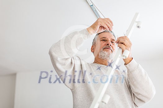 Senior man installing a ceiling light n a freshly renovated appartment Senior man installing a ceiling light n a freshly renovated appartment