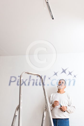 Senior man installing a ceiling light n a freshly renovated appartment Senior man installing a ceiling light n a freshly renovated appartment