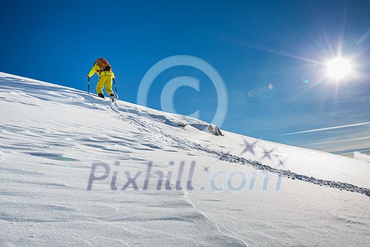 High altitude mountain explorer walking through deep snow in high mountains on a freezing winter day