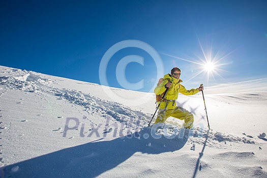 High altitude mountain explorer walking through deep snow in high mountains on a freezing winter day