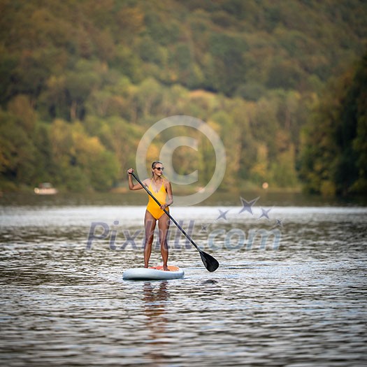 SUP Stand up paddle board concept - Pretty, young woman paddle boarding on a lovely lake in warm late afternoon light - shot from underwater SUP Stand up paddle board concept - Pretty, young woman paddle boarding on a lovely lake in warm late afternoon light - shot from underwater