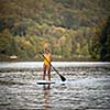SUP Stand up paddle board concept - Pretty, young woman paddle boarding on a lovely lake in warm late afternoon light - shot from underwater