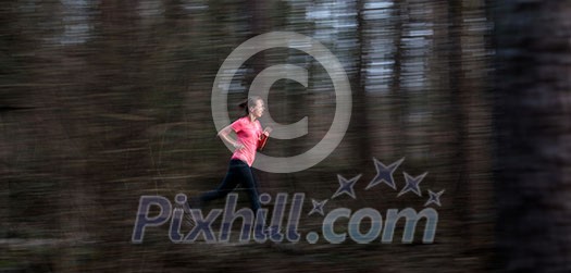 Young woman running outdoors in a forest, going fast (motion blurred image)